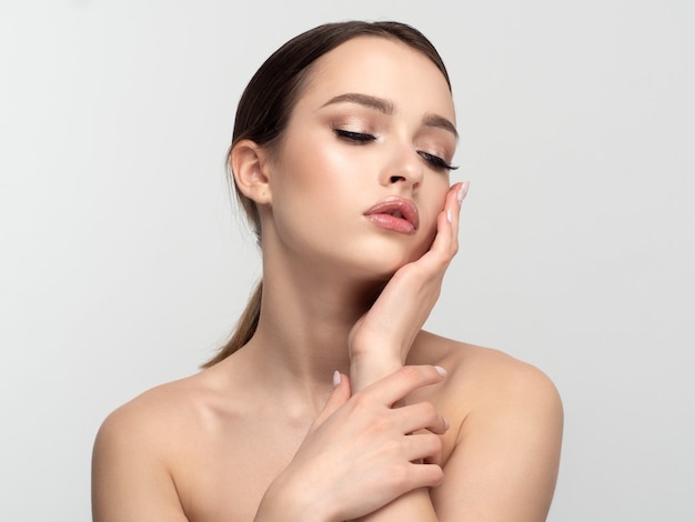 Portrait of young beautiful caucasian woman touching her face. Cleaning skin, skincare, cosmetology concept