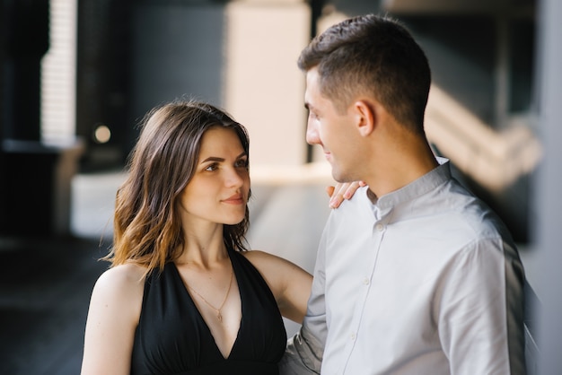 Portrait of a young beautiful couple. The girl looks into the eyes of her loved one and smiles. First date and the concept of tenderness