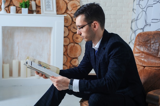 Portrait of young beautiful fashionable man with magazine in his hands