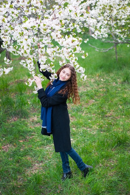 Portrait of a young beautiful fashionable woman in spring blossoming park.