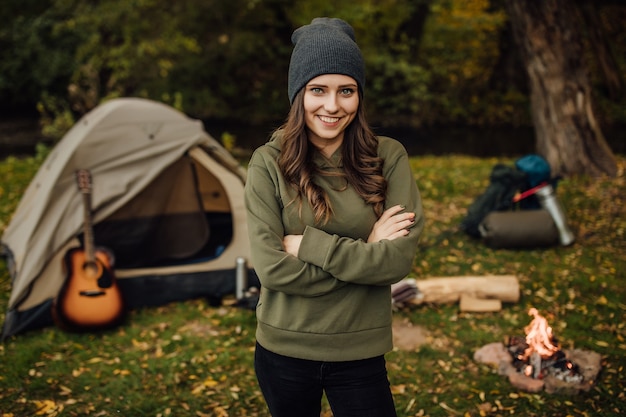 Portrait of young beautiful female tourist in the forest near tent