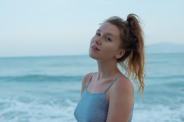 Portrait young beautiful girl on background embankment with sea ocean and island view smiling relaxing with closed eyes sunset deep breath fresh air