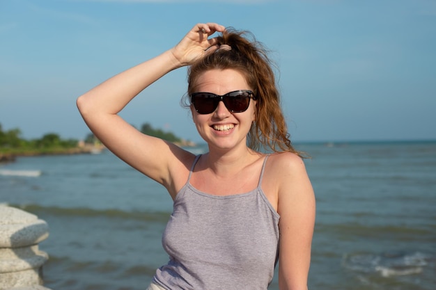 Portrait young beautiful girl on background embankment with sea ocean and island view smiling relaxing with closed eyes sunset