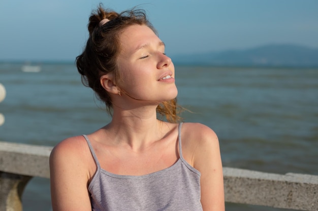 Portrait young beautiful girl on background embankment with sea ocean and island view smiling