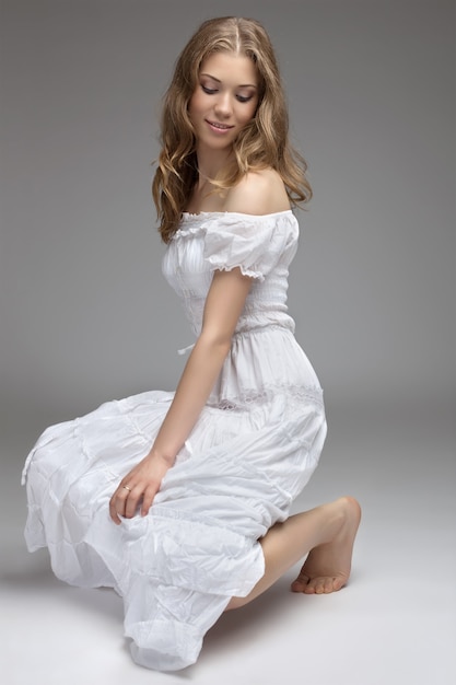 Portrait of the young beautiful girl of the blonde in studio. on gray background