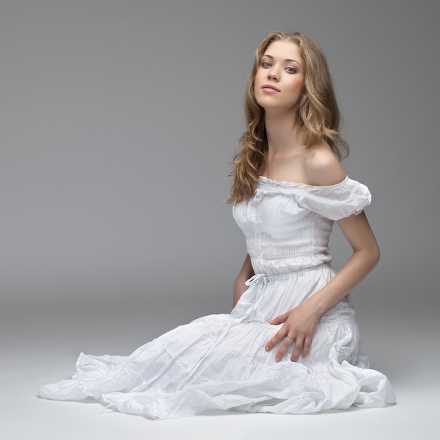 Portrait of the young beautiful girl of the blonde in studio. on gray background