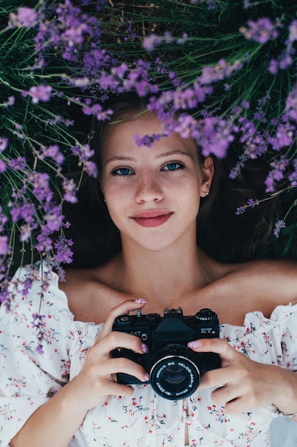 Portrait of a young beautiful girl in lavender bushes with an old camera in her hands