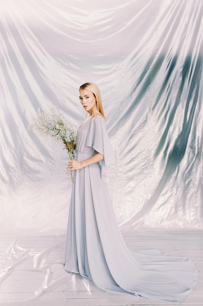 Portrait of a young beautiful girl in polyethylene with flowers on the background Fashion portrait