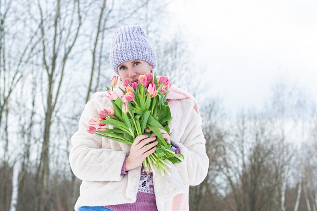 Portrait of a young beautiful girl in the street in winter with tulips