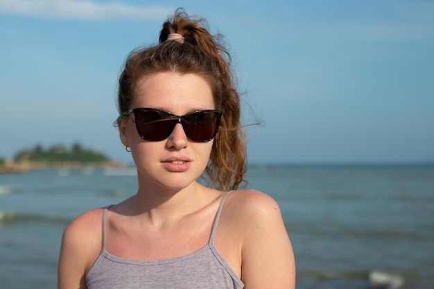 Portrait young beautiful girl in sunglasses on background embankment with sea ocean and island view