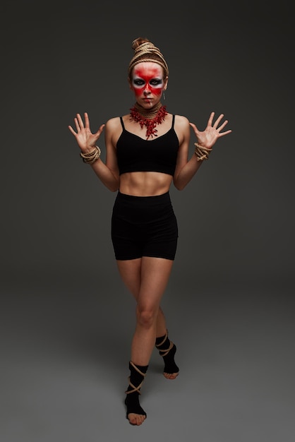 Portrait of young beautiful girl with colorful face painting with an animal flow move in studio against a gray background professional makeup Neck and hands are wrapped with ropes Victim Concept