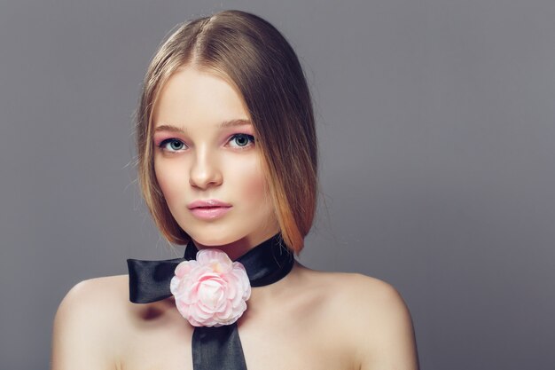 Portrait of young beautiful healthy woman with fancy pink rose ornament accessory