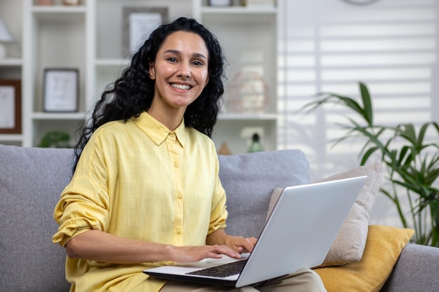 Portrait of young beautiful hispanic woman at home with laptop woman smiling and looking at camera