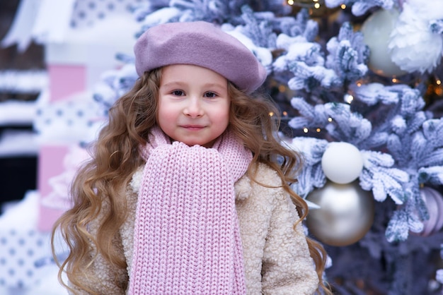 Portrait of young beautiful kid child girl in christmas decoration at winter snowy day near