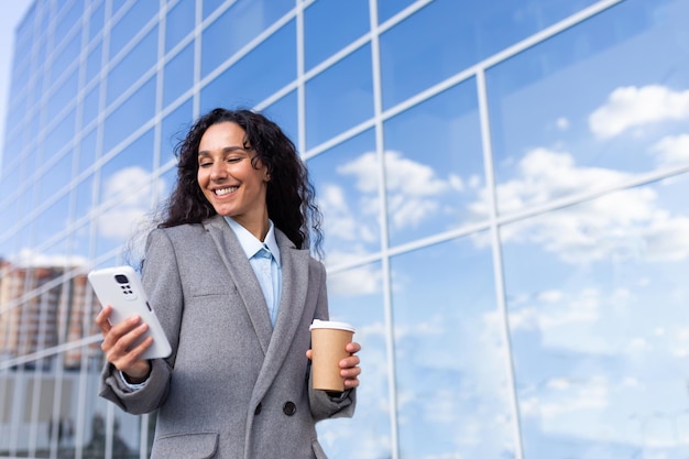 Portrait of a young beautiful latin american businesswoman in a suit walking outside near a glass