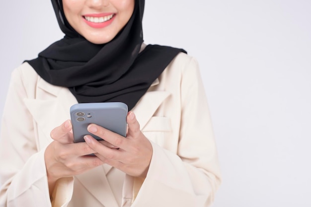 Portrait of young beautiful muslim woman in suit using smart phone over white background