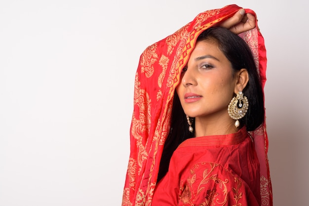 Portrait of young beautiful Persian woman wearing traditional clothing against white wall