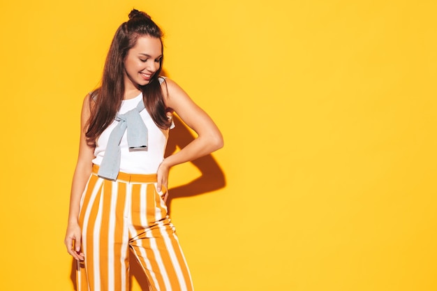 Portrait of young beautiful smiling female in trendy summer clothes Sexy carefree woman posing in studio Positive brunette model having fun and going crazy Cheerful and happy