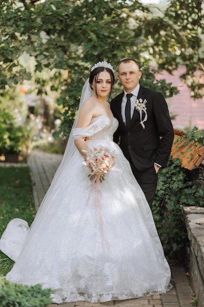 portrait of a young beautiful wedding couple in the garden the bride in an offtheshoulder wedding dress the groom in a black classic suit