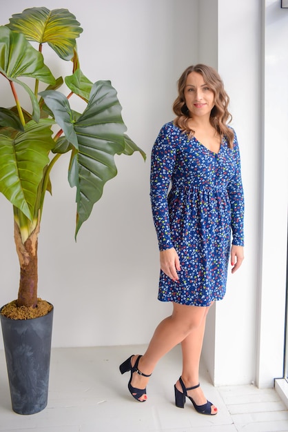 portrait of a young beautiful woman in a blue dress in a stylish modern interior near the window