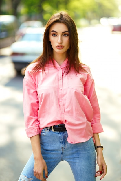 Portrait of Young and beautiful woman in casual clothes in the street. dressed in a pink shirt and jeans. spring / summer concept. relax time. girl with blue eyes. Enjoy street sunset