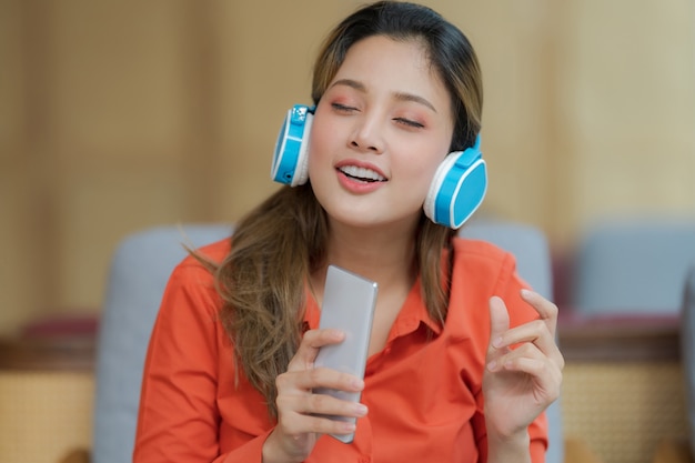 Portrait of young beautiful woman enjoying the music with smiling face sitting near window in creative office or cafe