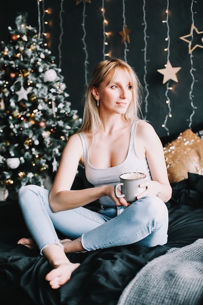 Portrait of a young beautiful woman in festive Christmas and New Year decorated interior