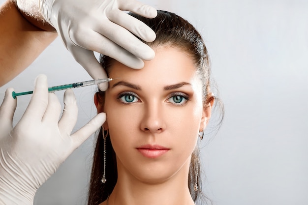 Portrait of a young, beautiful woman getting botox cosmetic injection