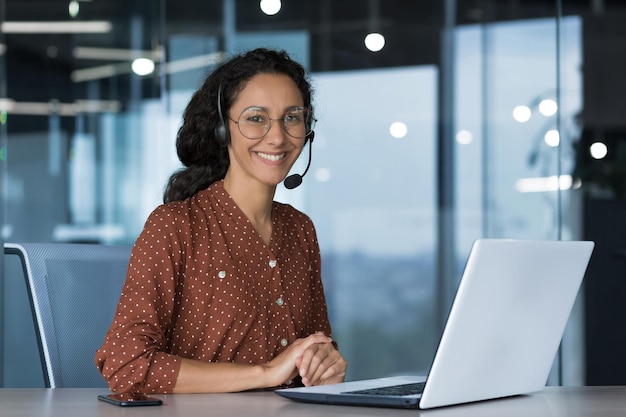 Portrait of young beautiful woman in glasses looking at camera and smiling arab woman using headset