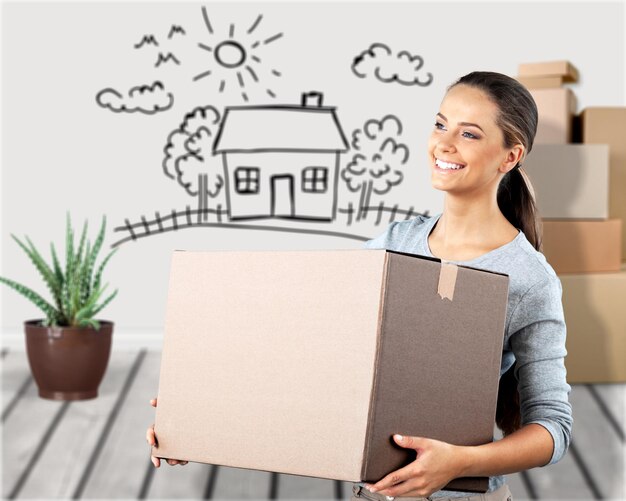 Photo portrait of young beautiful woman holding paper box in new room