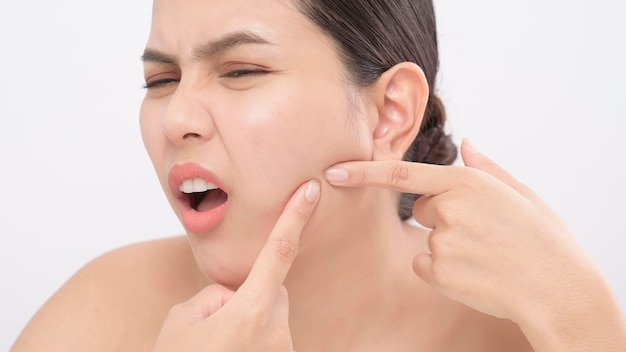 Portrait of young beautiful woman is checking her skin and popping pimple