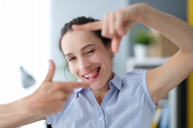 Portrait of young beautiful woman making frame with own hands creative ideas for photo concept