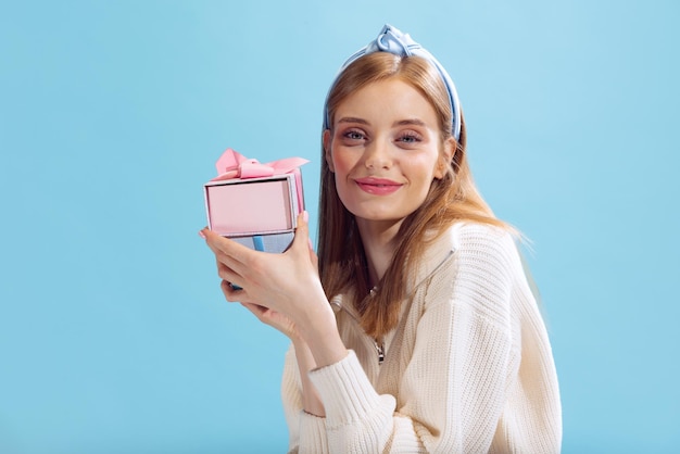 Portrait of young beautiful woman posing with present boxes isolated over blue studio background