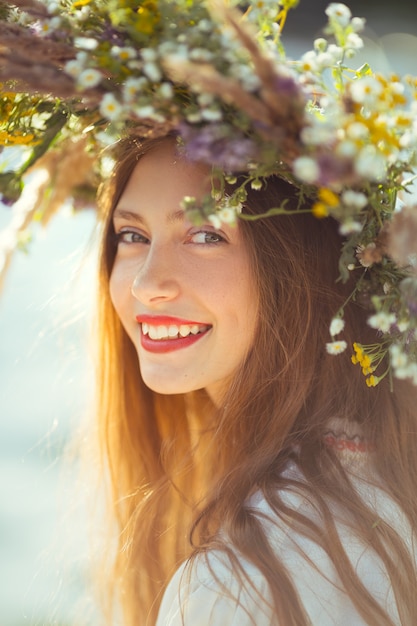 Portrait of Young beautiful woman wearing a wreath of wild flowers