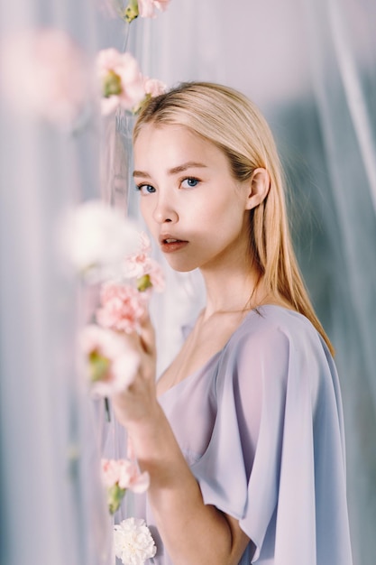 Portrait of a young beautiful woman white and pink flowers Fashion photography with polyethylene