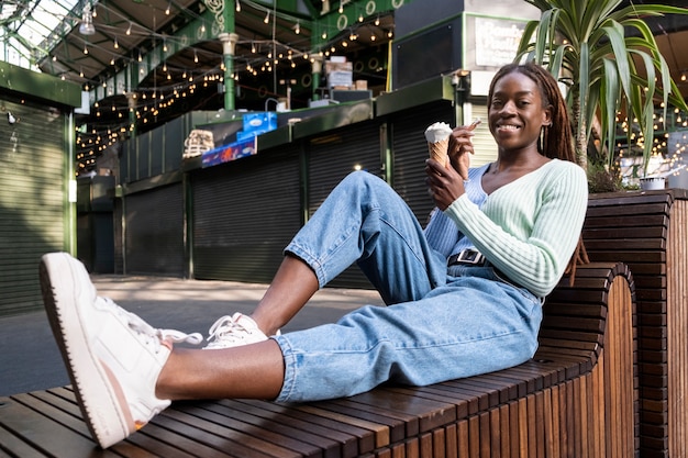 Portrait of young beautiful woman with afro dreadlocks enjoying an ice cream in the city