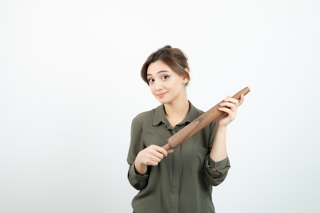 Portrait of young beautiful woman with wooden rolling pin standing. High quality photo