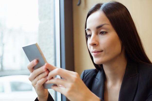 Portrait of Young beautiful woman working in the phone or using the Internet sitting in a cafe