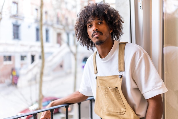 Portrait of a young black ethnic man on a balcony at home everyday situation apartment