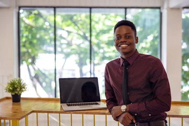 Portrait of a young black man using a laptop in a working environment, either an African businessman or a student.