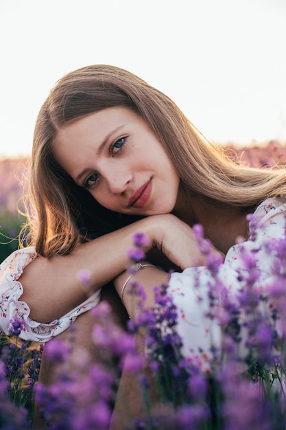 Portrait of a young blonde girl in a lavender field in the summer at sunset