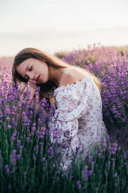 Portrait of a young blonde girl in a lavender field in the summer at sunset