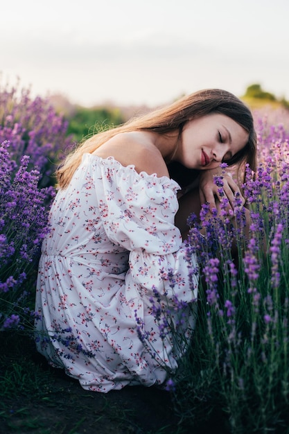 Portrait of a young blonde girl in a lavender field in the summer at sunset