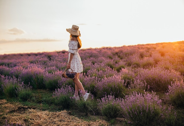 Portrait of a young blonde girl in a lavender field in the summer at sunset