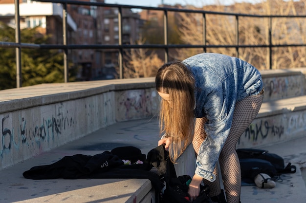 Portrait of a young blonde woman picking up her backpack after her workout on street