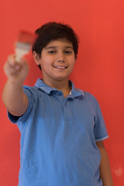 Portrait of a young boy painter with a brush in his hand in front of colored background