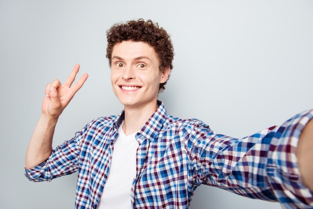 Portrait of young brunet man making selfie gesturing v-sign symbol