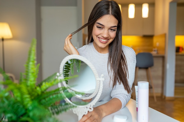 Portrait of a young brunette cosmetics beauty. Happy young woman looking on mirror