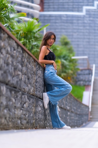 Portrait of a young brunette model in a black cap and jeans in the city lifestyle