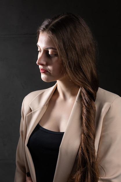 Portrait of a young brunette with long hair in the studio Dramatic photo in dark colors